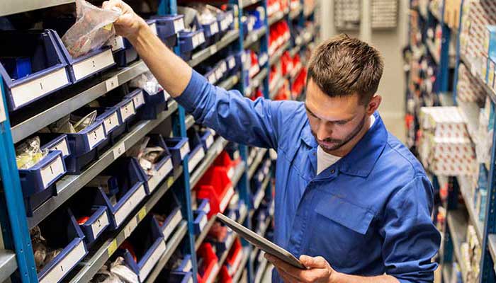 A blue-clad GMC Service Center technician checking the spare parts inventory